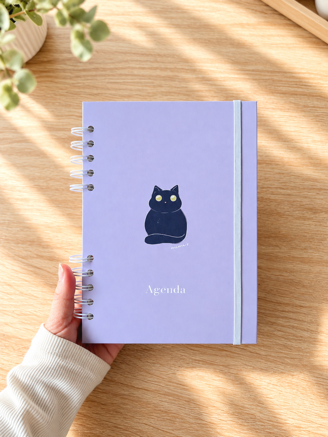 Agenda 2027 de semana vista con portada lila pastel y una ilustración de un gato negro, diseñada y encuadernada a mano.